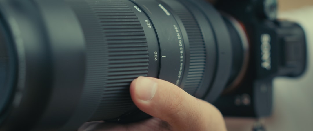 Close-up of a hand adjusting the focus ring on a camera lens