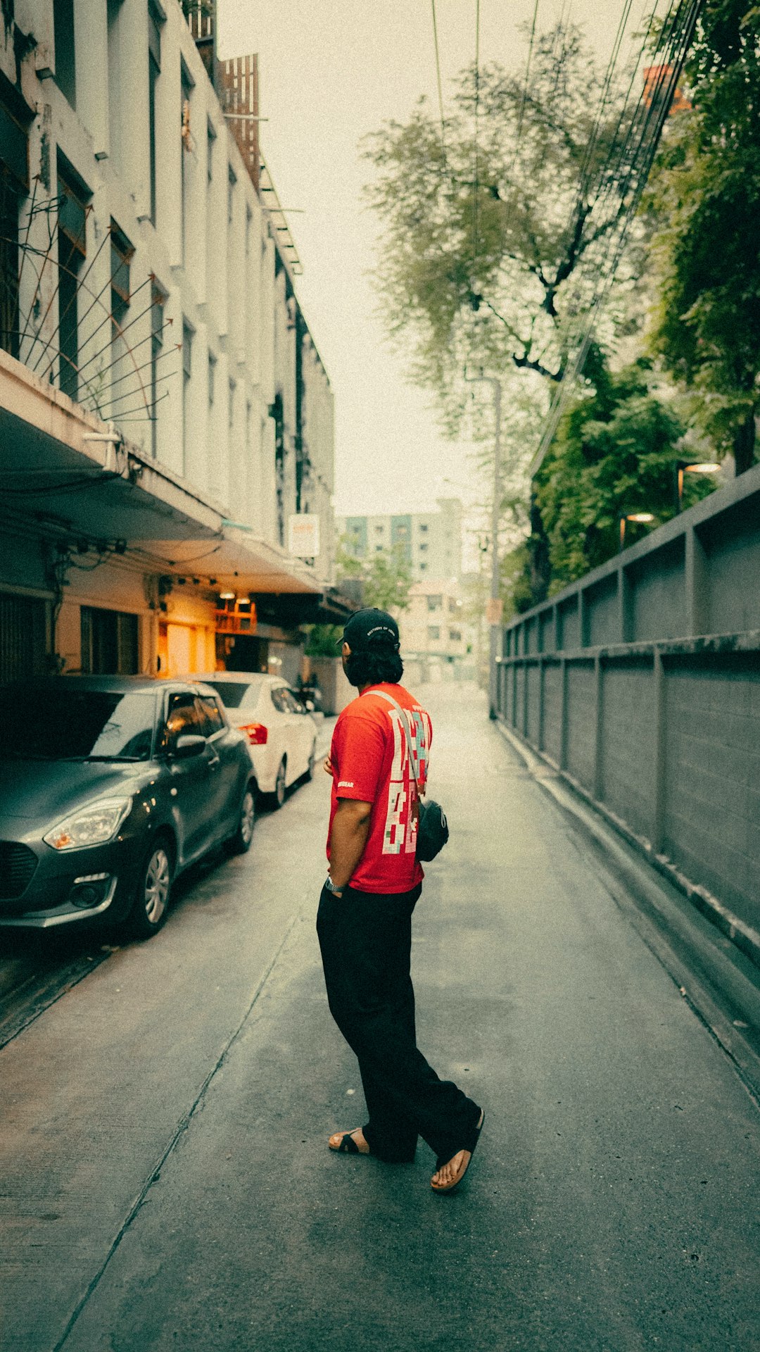 Photographer walking through a city street with a camera strap around his shoulder