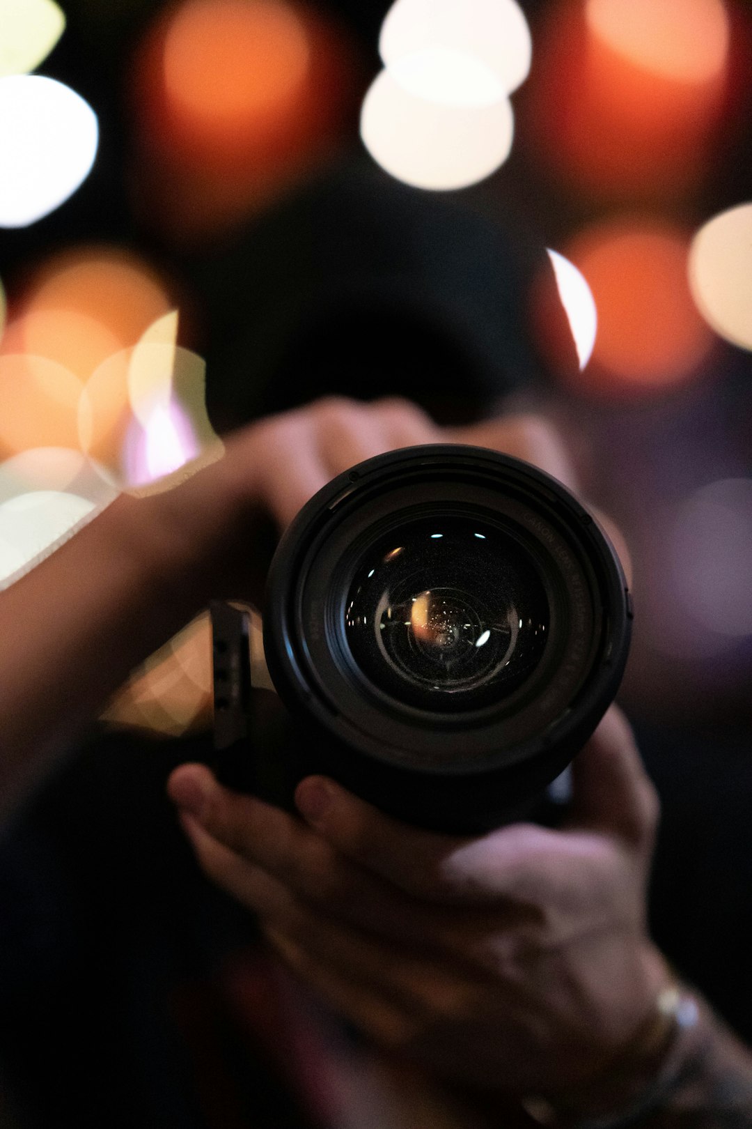 Photographer holding a camera lens, comparing prime and zoom options